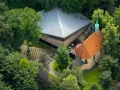 Luftaufnahme von Annaberg Haltern: Ein Gotteshaus mit rotem Ziegeldach und grüner Turmspitze, daneben ein moderner Bau mit Pyramiden-Dach, umgeben von üppigem Grün.