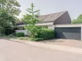 Modernes Haus mit Garage und gepflegtem Garten. Eine Einliegerwohnung könnte hier Vorteile wie zusätzliche Mieteinnahmen bieten, aber auch Nachteile wie Lärm oder Privatsphäreverlust mit sich bringen.
