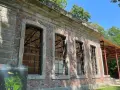 Die Orangerie Herten, ein historisches Gebäude mit großen Fensterfronten, steht im Schatten von Bäumen.