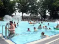 Menschen genießen einen sonnigen Tag im Parkbad Nord. Kinder planschen, rutschen und spielen in den Wasserbällen.