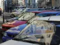 Autos parken in einer Reihe im Frankenberger Viertel Aachen. Menschen sitzen an einem Tisch im Hintergrund.