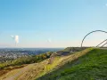 Blick über die Halde Recklinghausen mit der markanten Hängebrücke und rauchenden Schloten in der Ferne.