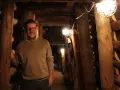 Mann in der Maschinenhalle Scherlbeck, umgeben von Holzverstrebungen und Grubenlampen.