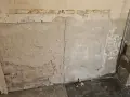 Abblätternder Putz an einer Wand mit freiliegenden Ziegeln und einer Steckdose. Vorsicht bei der Renovierung, um **asbest erkennen** zu können.