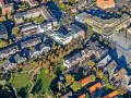 Luftaufnahme eines Wohngebiets mit Mehrfamilienhäusern und Einfamilienhäusern. Die Bäume zeigen Herbstlaub. Ein zentraler Platz ist zu sehen. Hier könnte man den Mietspiegel Voerde studieren.