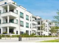 Moderne weiße Wohnanlage mit Balkonen und Bäumen. Ein Blick auf den Quadratmeterpreis Eigentumswohnung in dieser Gegend.