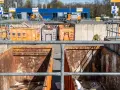 Große orange Container auf einem Recyclinghof in Bottrop. Ein kleiner gelber Bagger steht bereit.