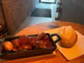 Herzhafte Steiger Wurst in Tomatensoße mit einem Brötchen auf einem Holztisch.
