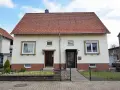 Zwei Eingänge an einem hellen Haus mit rotem Ziegeldach. Ein potenzielles Projekt für "altes Haus renovieren Kosten".