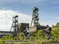 Ein Paar genießt eine Fahrradtour in Recklinghausen, vorbei an alten Fördertürmen und Industriegebäuden.