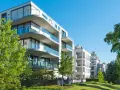 Moderne Wohngebäude mit Balkonen und Glasgeländern, umgeben von Grünflächen. Hier wird in Recklinghausen gebaut.