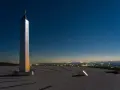 Die Sonnenuhr in Herten ragt unter einem sternenklaren Nachthimmel empor. Ein glänzender Obelisk wirft lange Schatten auf die gepflasterte Fläche.