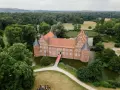 Schloss Recklinghausen, ein imposantes Wasserschloss, umgeben von grünen Bäumen und einem Teich. Eine rote Teppich führt zur Eingangstür.