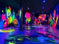 Ein leuchtendes Indoor-Minigolf-Paradies mit Neon-Wänden, die bunte Monster und Pilze zeigen.