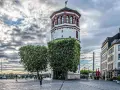 Düsseldorfer Rheinturm mit Bäumen und Gebäuden. Die Immobilienpreise in Oberbilk sind ein Thema, das viele interessiert.