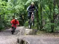 Zwei Mountainbiker springen über die Holzbox auf dem Halde Hoppenbruch Trail.