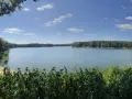 Ein ruhiger Tag am Hullerner Stausee. Grüne Bäume säumen das Ufer, das Wasser glitzert unter blauem Himmel mit weißen Wolken.
