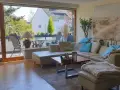 Gemütliches Wohnzimmer mit Ledercouch, Blick auf Balkon und Garten. Ein schönes Zuhause, das die Immobilienpreise in Ratingen widerspiegelt.
