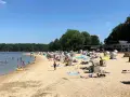 Sonniger Tag am **Haltern am See Strand** mit vielen Badegästen, Strandkörben und Bäumen im Hintergrund.