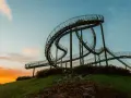 Die Achterbahn-Skulptur Tiger & Turtle auf einer Halde im Ruhrgebiet, im warmen Licht des Sonnenuntergangs.