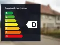 Energieeffizienzklasse D auf einem dunklen Hintergrund. Das Haus im Hintergrund hat eine braune Ziegeldach.