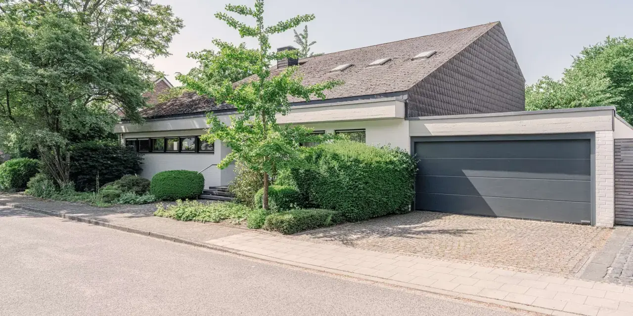 Modernes Haus mit Garage und gepflegtem Garten. Eine Einliegerwohnung könnte hier Vorteile wie zusätzliche Mieteinnahmen bieten, aber auch Nachteile wie Lärm oder Privatsphäreverlust mit sich bringen.