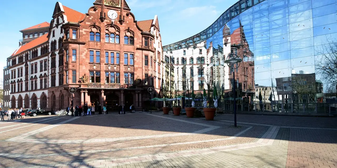 Historisches Gebäude und moderne Glasfassade spiegeln sich auf dem Platz. Hier könnte man sich über den Mietspiegel Dortmund informieren.