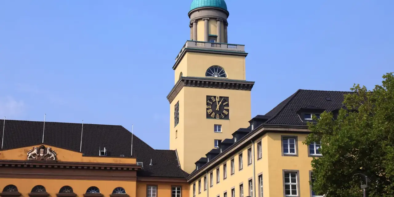 Gelber Turm mit Uhr und historischen Gebäuden in Witten. Die Immobilienpreise in Witten sind hier ein Thema.
