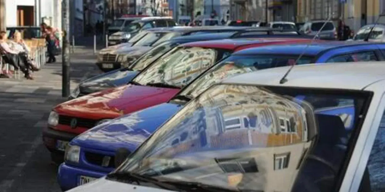 Autos parken in einer Reihe im Frankenberger Viertel Aachen. Menschen sitzen an einem Tisch im Hintergrund.