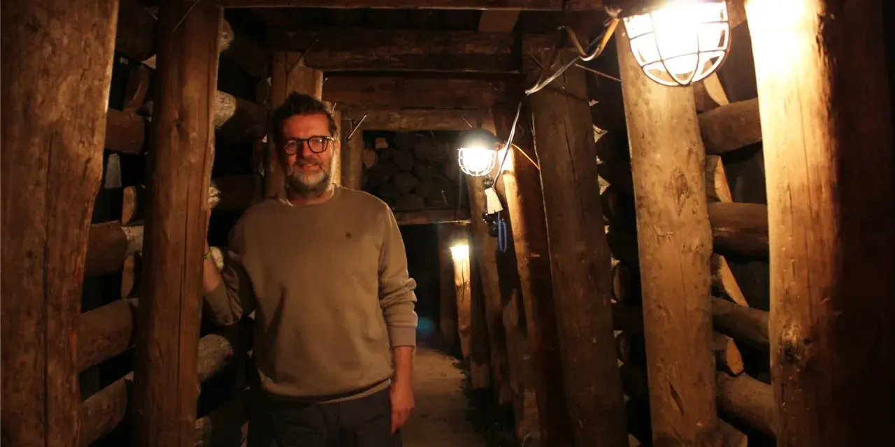 Mann in der Maschinenhalle Scherlbeck, umgeben von Holzverstrebungen und Grubenlampen.