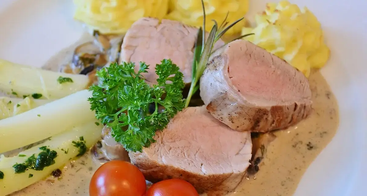 Zartes Schweinefilet mit Kartoffelröschen, Spargel und einer cremigen Sauce, serviert wie in einer alten Dorfbrennerei.