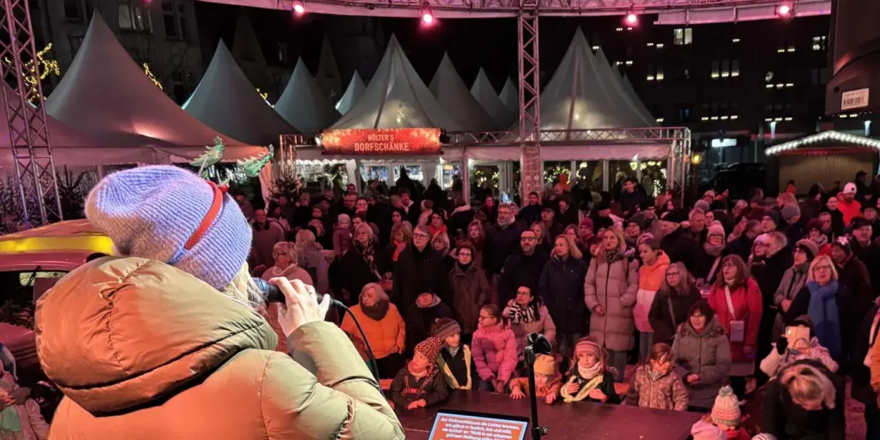 Menschenmenge auf dem Castrop Rauxel Weihnachtsmarkt vor der Dorfkneipe, eine Frau singt ins Mikrofon.