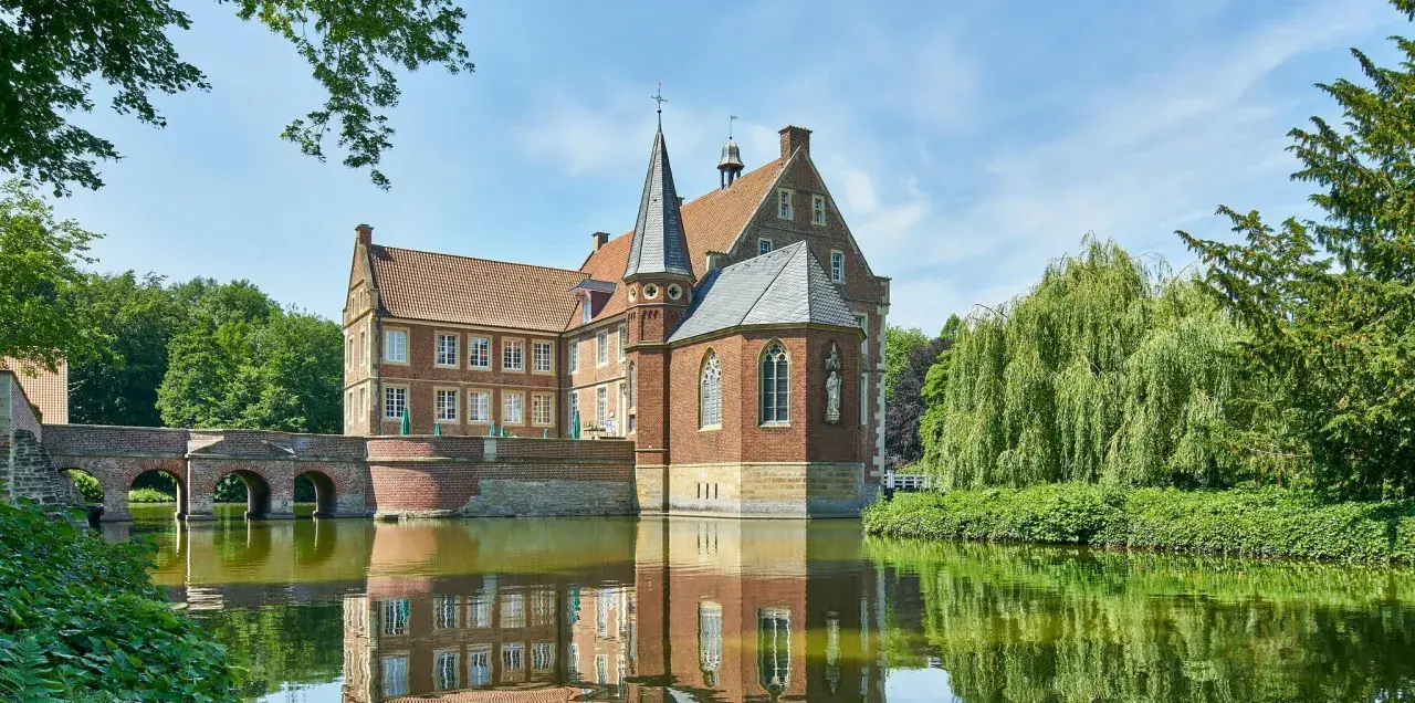 Wasserschloss in Haltern am See, umgeben von einem Wassergraben und üppiger Vegetation.