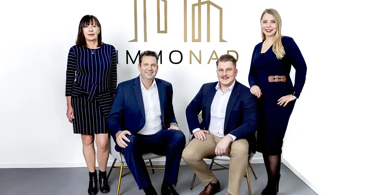 Immobilienpreise Oberhausen: Vier professionelle Makler des Unternehmens "MMONAD" posieren vor ihrem Logo.