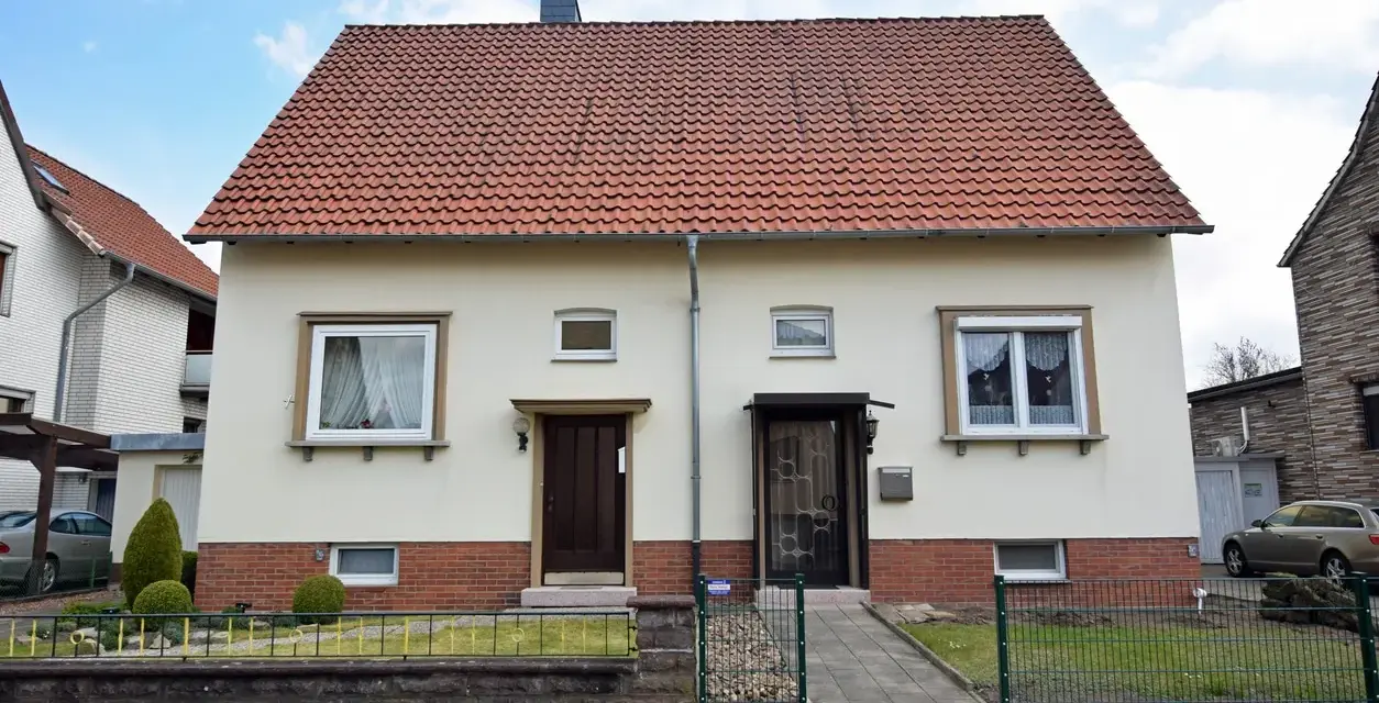 Zwei Eingänge an einem hellen Haus mit rotem Ziegeldach. Ein potenzielles Projekt für "altes Haus renovieren Kosten".