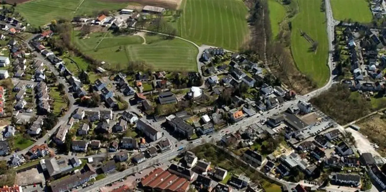Luftaufnahme eines Dorfes mit Häusern, Straßen und Feldern.