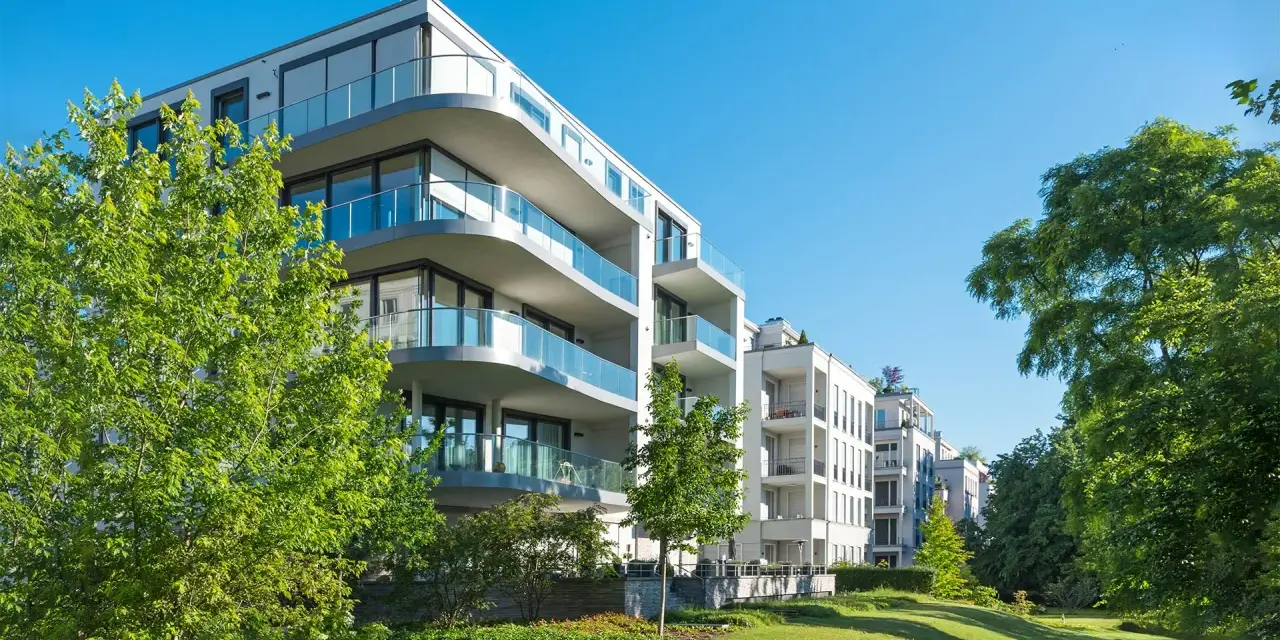 Moderne Wohngebäude mit Balkonen und Glasgeländern, umgeben von Grünflächen. Hier wird in Recklinghausen gebaut.