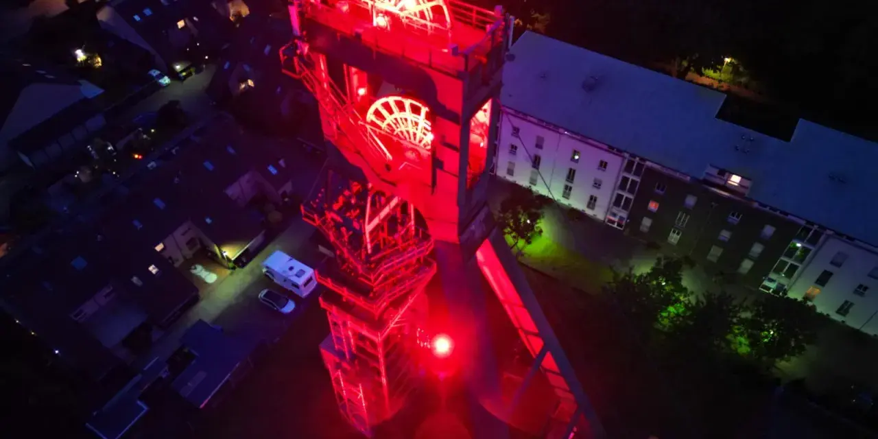 Der beleuchtete Förderturm des Erzschacht Marl erstrahlt in rotem Licht.