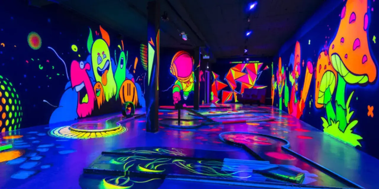 Ein leuchtendes Indoor-Minigolf-Paradies mit Neon-Wänden, die bunte Monster und Pilze zeigen.