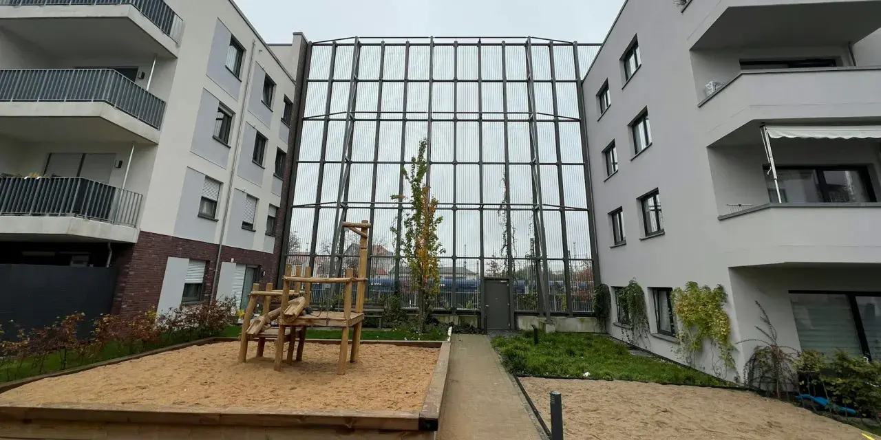 Moderne Wohnanlage mit Spielplatz und Sandkasten. Die Fassaden und Balkone sind hellgrau. Die Immobilienpreise in Leverkusen spiegeln die Attraktivität der Stadt wider.