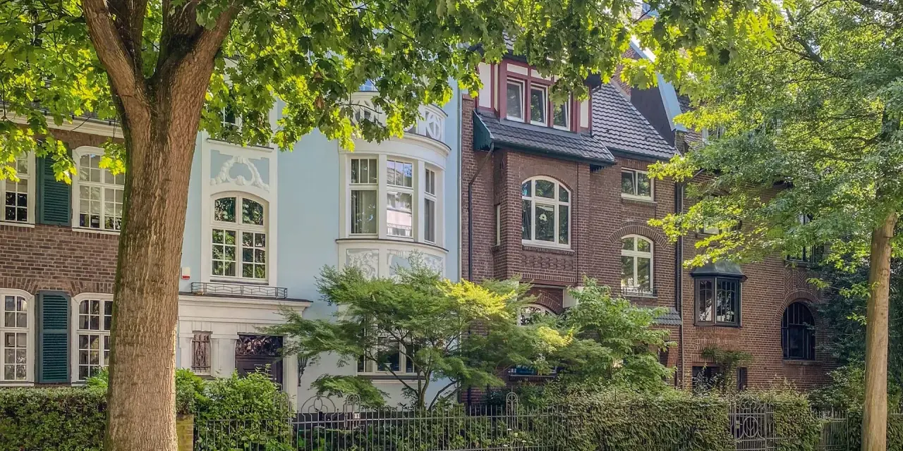 Schöne Häuser mit Ziergiebeln und Erkerfenstern, umgeben von üppigem Grün. Ein idyllisches Bild für wohnen in Krefeld.