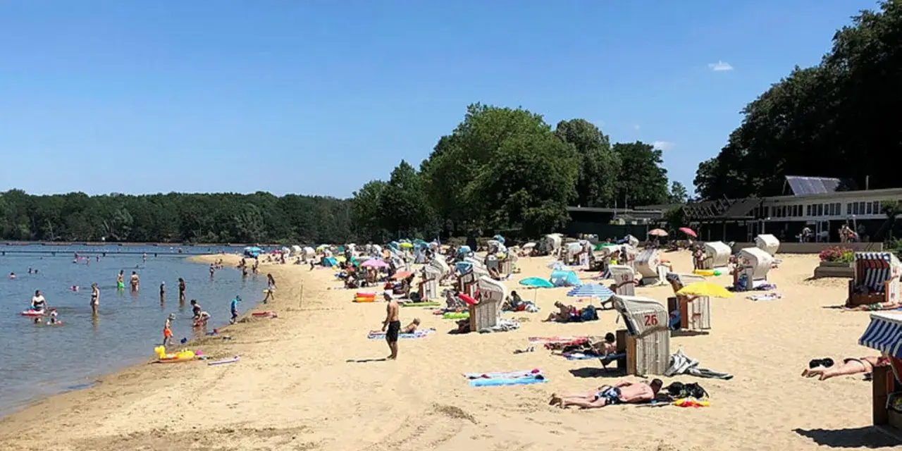 Sonniger Tag am **Haltern am See Strand** mit vielen Badegästen, Strandkörben und Bäumen im Hintergrund.