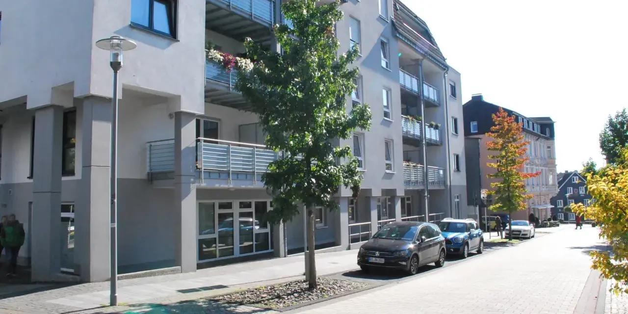 Moderne Wohngebäude mit Balkonen und Autos auf der Straße. Ein Baum steht vor einem Gebäude. Informationen zum Mietspiegel Wermelskirchen sind hier nicht ersichtlich.