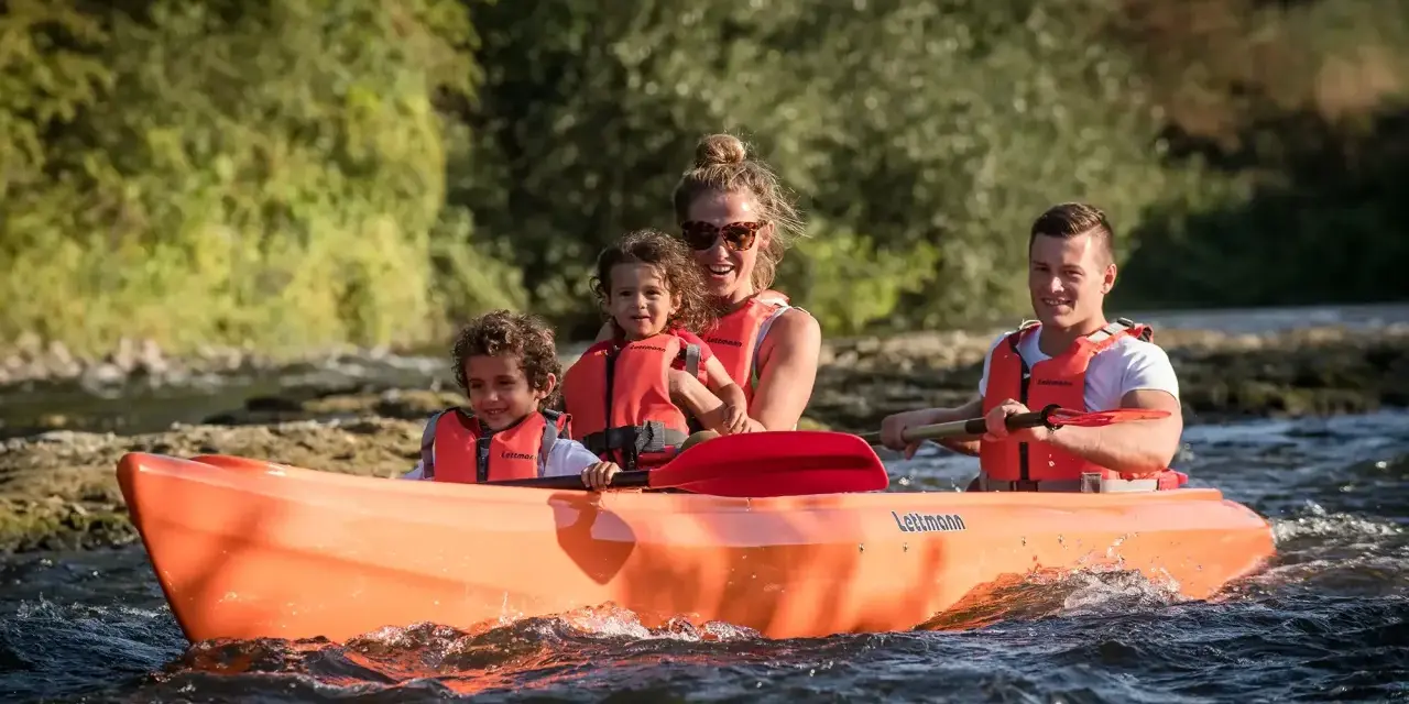 Familie genießt eine Fahrt im Kanu auf der Lippe, Kinder und Eltern mit Schwimmwesten.