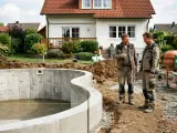 Zwei Bauarbeiter besprechen den Fortschritt eines Pools. Sie scheinen Wege zu finden, den **Bauzwang umgehen** zu können, indem sie kreative Lösungen für die Herausforderungen auf der Baustelle finden.