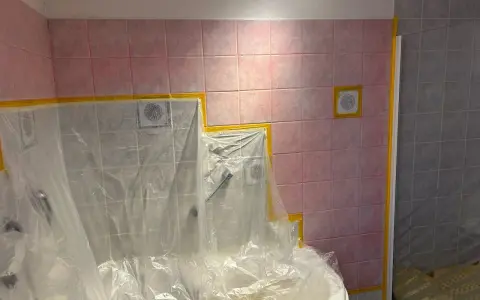 Badezimmerfliesen werden für das Streichen in der Mietwohnung abgeklebt.