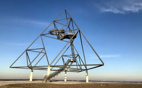 Das Tetraeder auf der Halde Beckstraße in Bottrop, ein Wahrzeichen der Industriekultur, ragt gegen einen blauen Himmel.