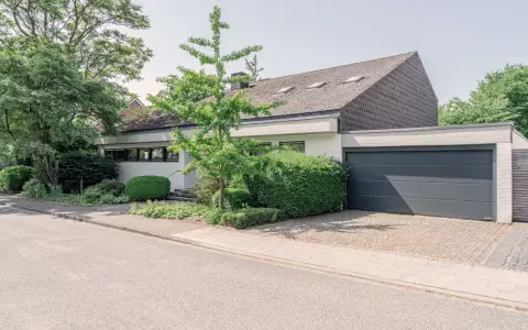 Modernes Haus mit Garage und gepflegtem Garten. Eine Einliegerwohnung könnte hier Vorteile wie zusätzliche Mieteinnahmen bieten, aber auch Nachteile wie Lärm oder Privatsphäreverlust mit sich bringen.