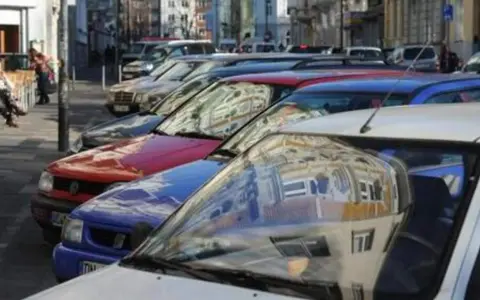 Autos parken in einer Reihe im Frankenberger Viertel Aachen. Menschen sitzen an einem Tisch im Hintergrund.