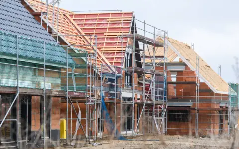 Neubau-Reihenhäuser in Moers im Rohbau, Gerüste umgeben die Ziegelbauten. Die steigenden immobilienpreise moers spiegeln sich in solchen Projekten wider.